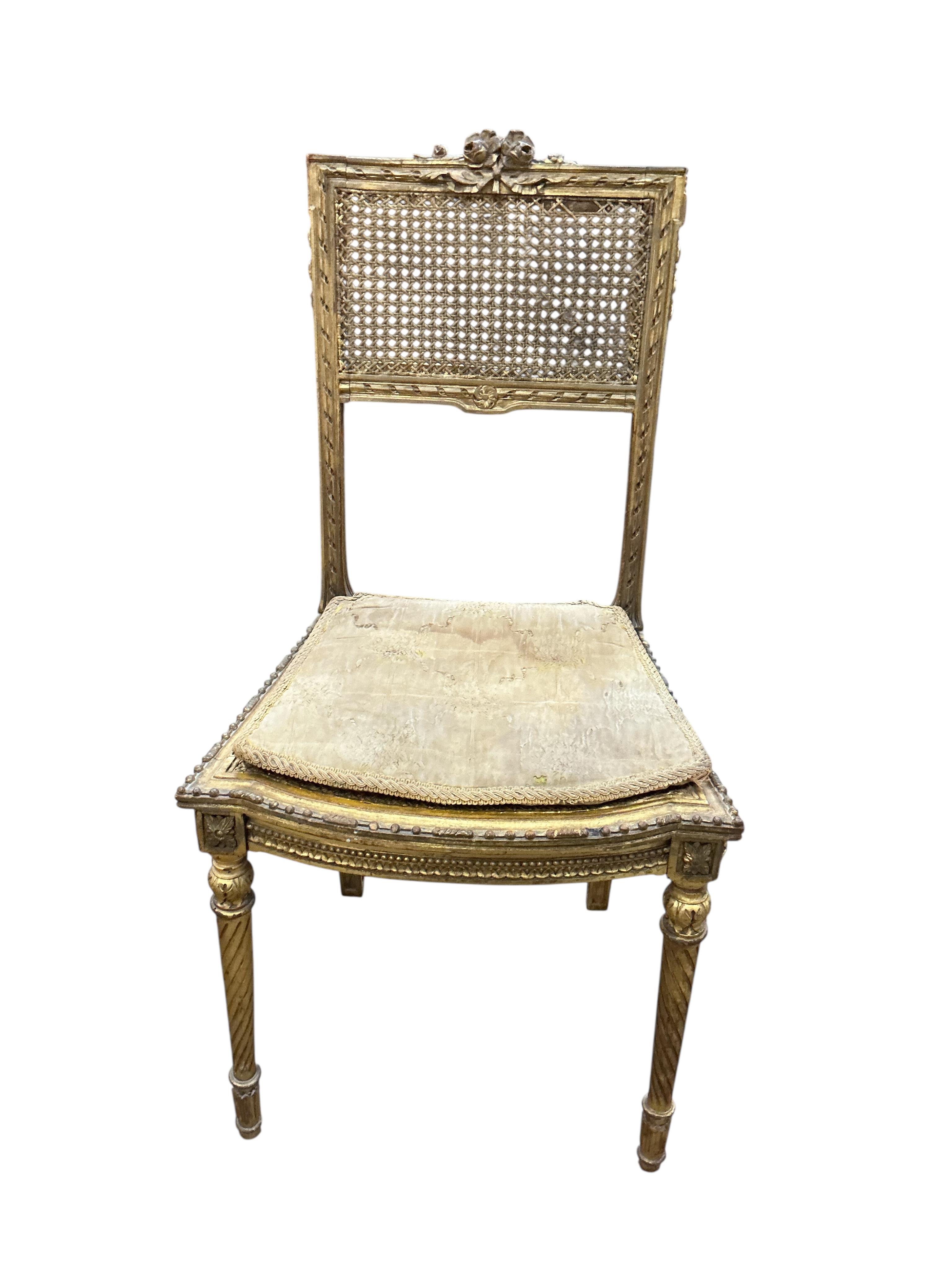 A late 19th century French Louis XVI style open elbow chair with cane seat, a matching side chair and another giltwood side chair